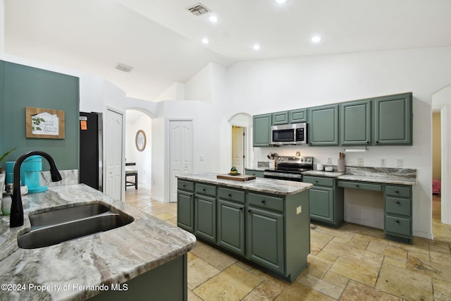 kitchen featuring high vaulted ceiling, green cabinets, sink, a kitchen island, and stainless steel appliances