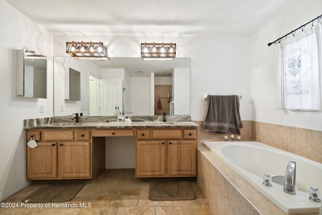 bathroom featuring tiled tub and vanity