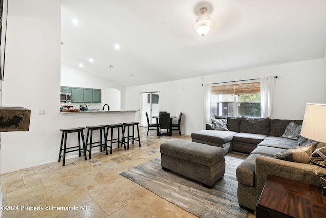 living room featuring ceiling fan, sink, and vaulted ceiling