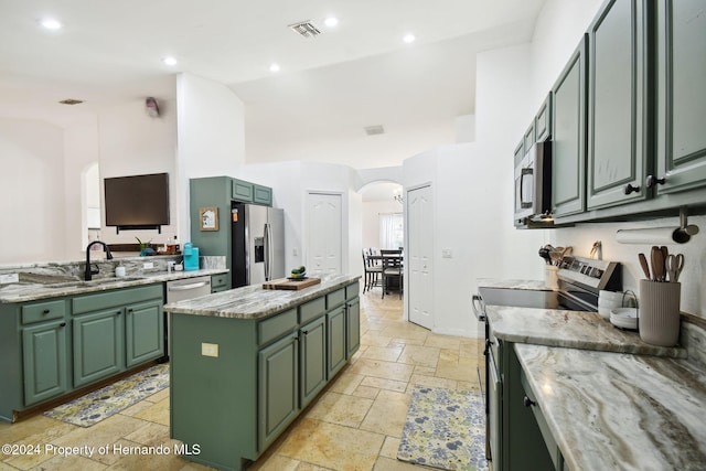 kitchen with appliances with stainless steel finishes, a kitchen island, green cabinetry, and sink