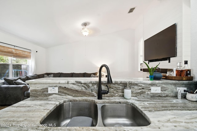 kitchen featuring light stone counters, sink, and lofted ceiling