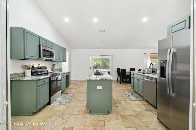 kitchen featuring lofted ceiling, sink, green cabinetry, appliances with stainless steel finishes, and a kitchen island