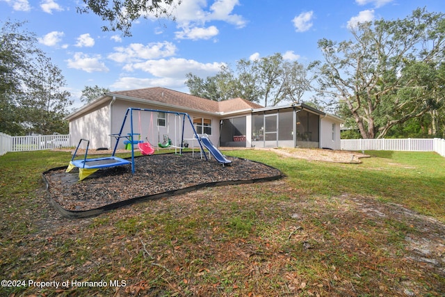 rear view of property with a yard, a playground, and a sunroom