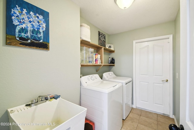 laundry room featuring a textured ceiling, washer and dryer, light tile patterned floors, and sink