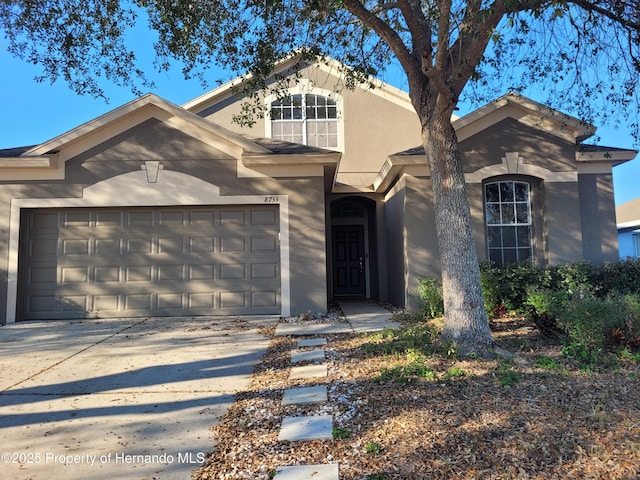 view of front facade featuring a garage, concrete driveway, and stucco siding