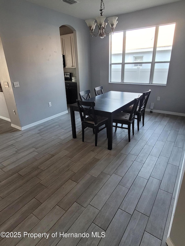 dining area with dark wood-type flooring, arched walkways, and baseboards