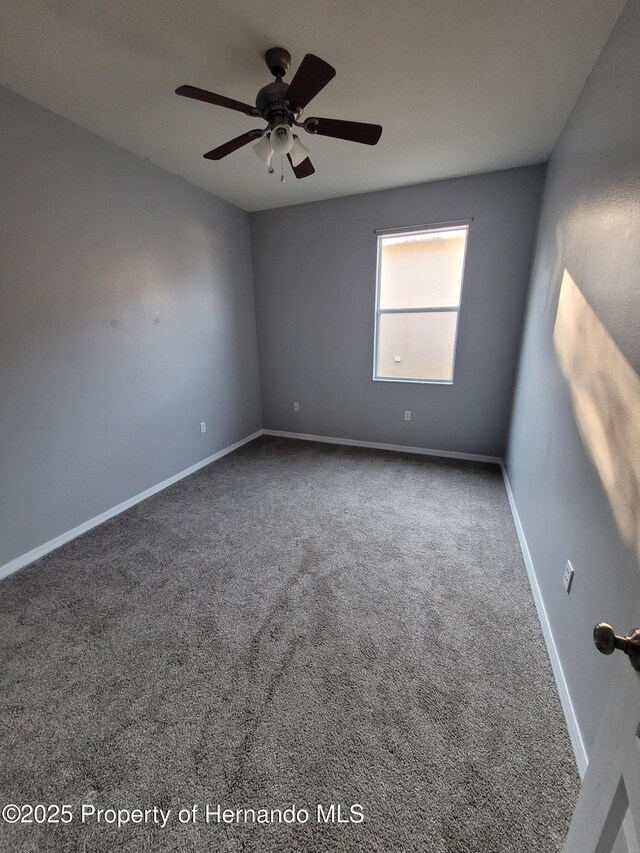 carpeted empty room featuring a ceiling fan and baseboards