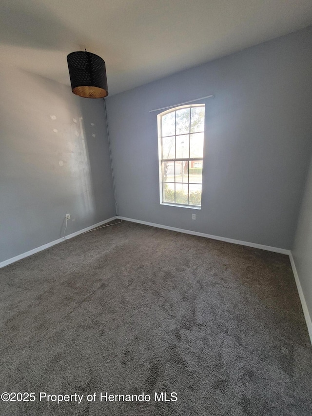 carpeted empty room featuring baseboards