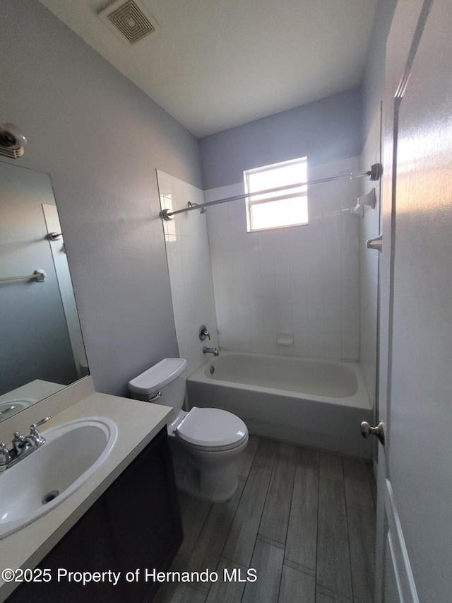 bathroom featuring wood finish floors, bathtub / shower combination, visible vents, toilet, and vanity