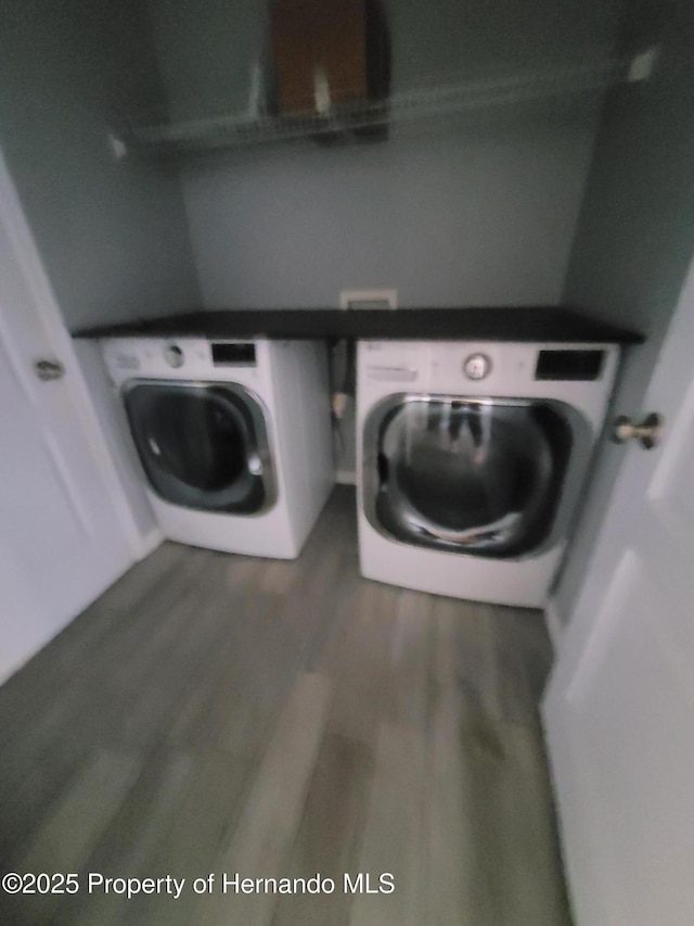 laundry area featuring laundry area, washing machine and clothes dryer, and wood finished floors