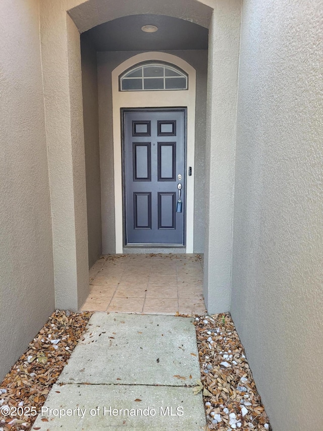 doorway to property featuring stucco siding