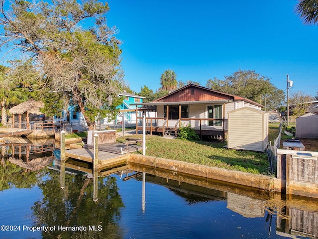 rear view of house featuring a deck with water view and a storage shed