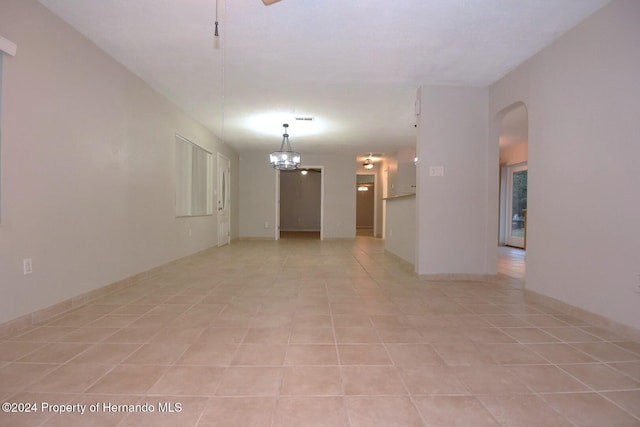 spare room featuring light tile patterned floors and a chandelier