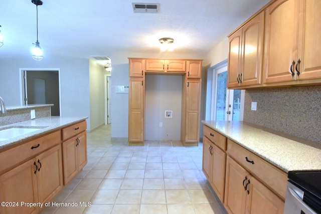 kitchen featuring light brown cabinetry, light stone counters, sink, and decorative light fixtures