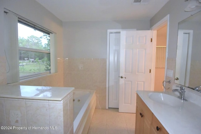 bathroom featuring tile patterned floors, vanity, a tub to relax in, and tile walls