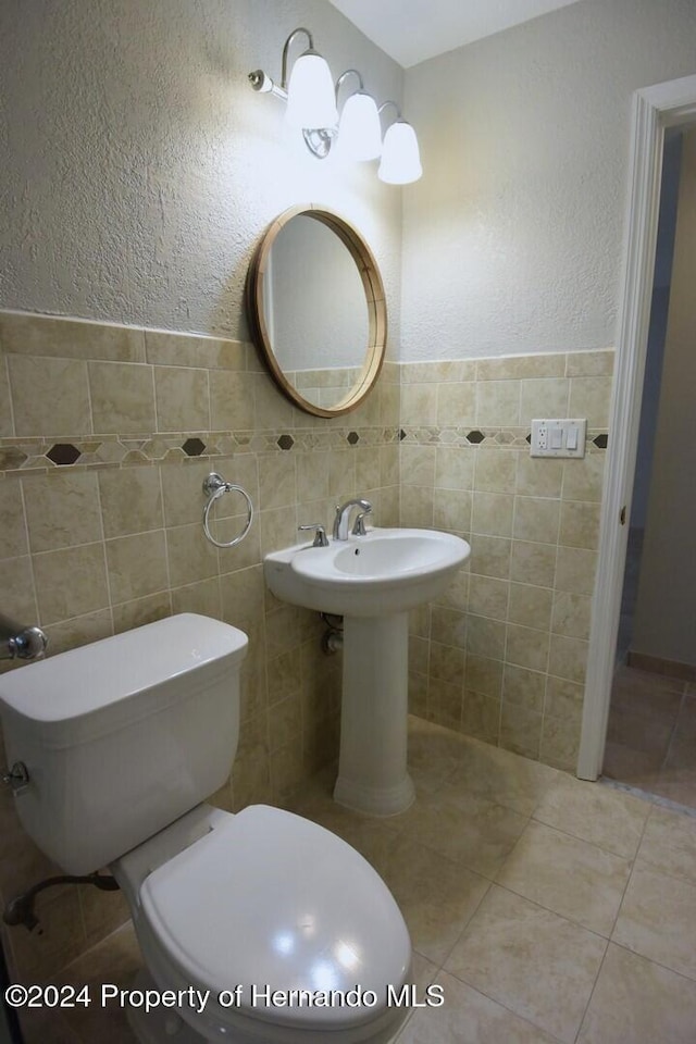 bathroom with tile patterned floors, tile walls, and toilet