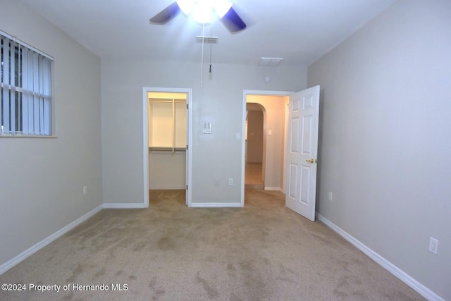 unfurnished bedroom featuring ceiling fan, light colored carpet, a spacious closet, and a closet