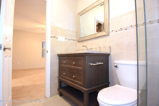 bathroom with toilet, vanity, tile patterned floors, and tile walls