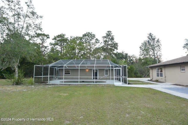 rear view of property featuring a yard and glass enclosure