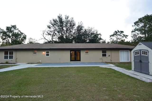 rear view of house with a lawn, a storage shed, and a patio