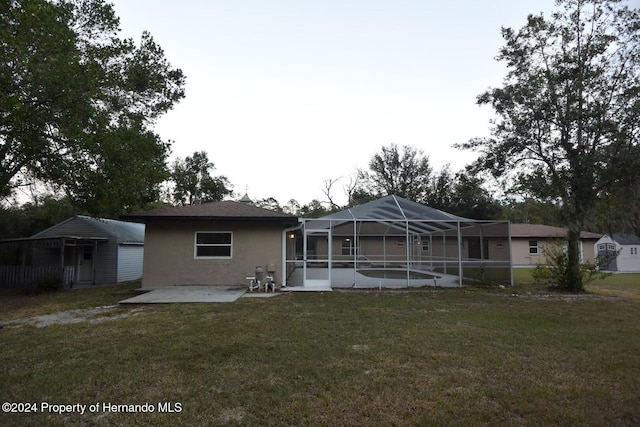 rear view of property with a lawn, a lanai, and a patio