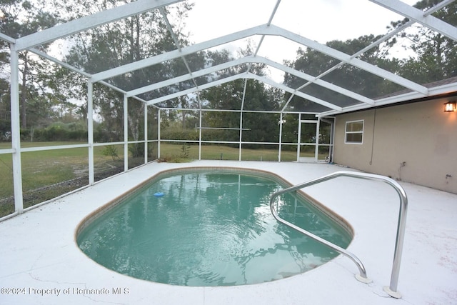 view of swimming pool featuring glass enclosure, a patio area, and a yard