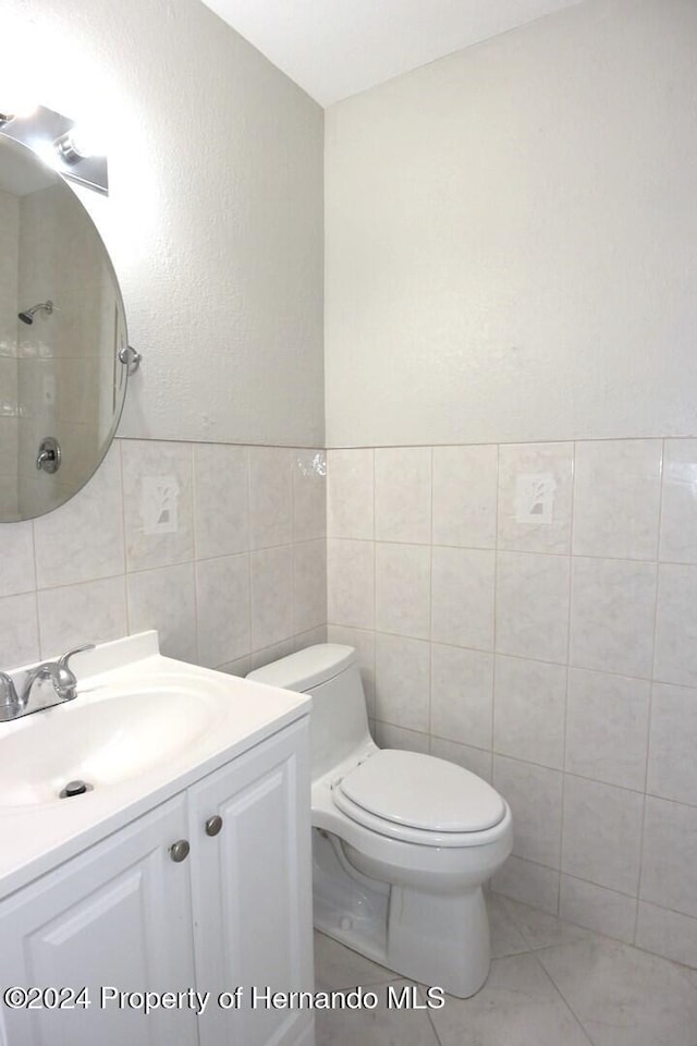 bathroom with vanity, tile walls, and toilet