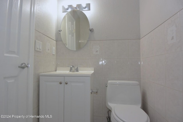 bathroom featuring vanity, tile walls, and toilet