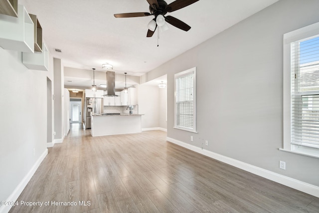 unfurnished living room with light hardwood / wood-style flooring, ceiling fan, and sink