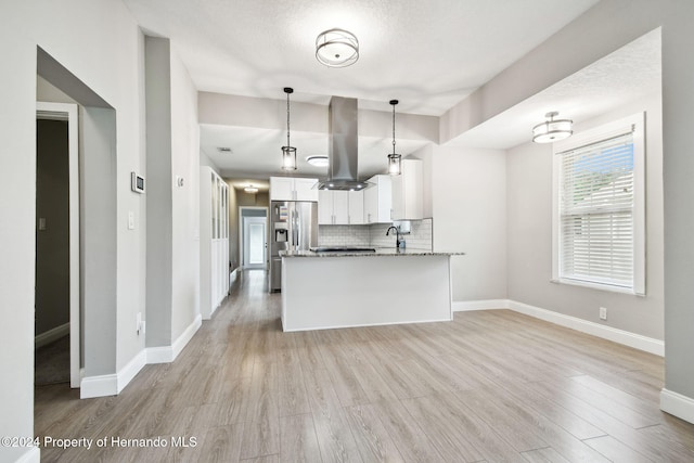 kitchen featuring hanging light fixtures, tasteful backsplash, dark stone countertops, island range hood, and white cabinets