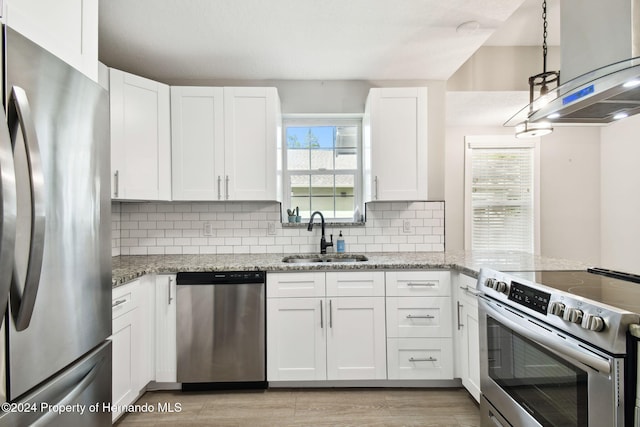 kitchen featuring appliances with stainless steel finishes, white cabinetry, exhaust hood, and sink