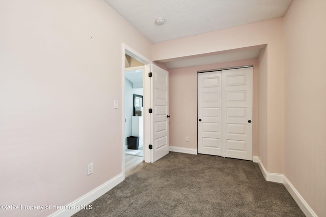 unfurnished bedroom featuring a closet and dark carpet