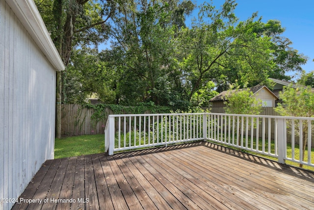 wooden deck featuring an outbuilding and a lawn