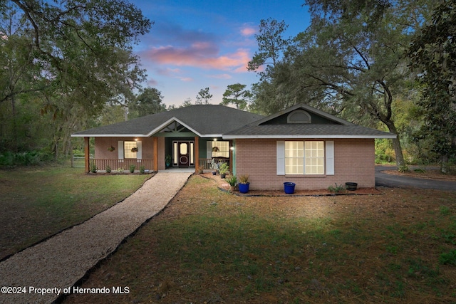 single story home with a lawn and a porch