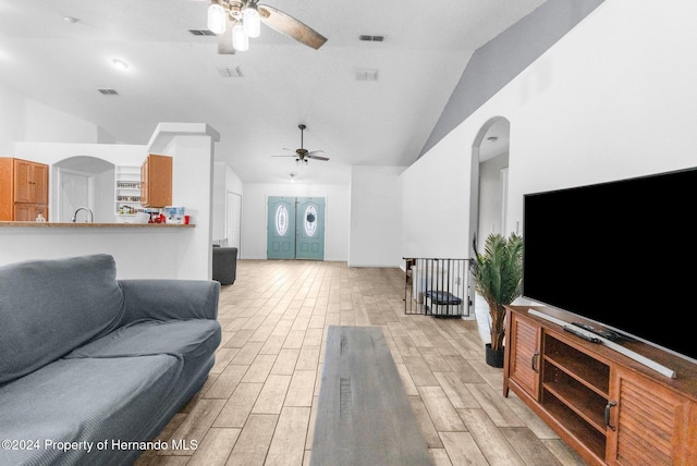 living room featuring ceiling fan, light wood-type flooring, and vaulted ceiling