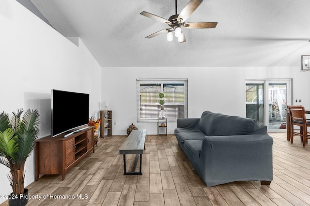 living room featuring a textured ceiling, light wood-type flooring, ceiling fan, and vaulted ceiling