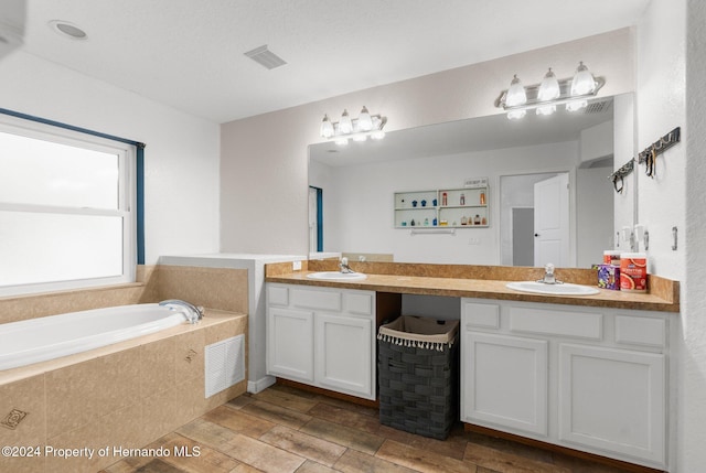 bathroom with hardwood / wood-style floors, vanity, and a relaxing tiled tub