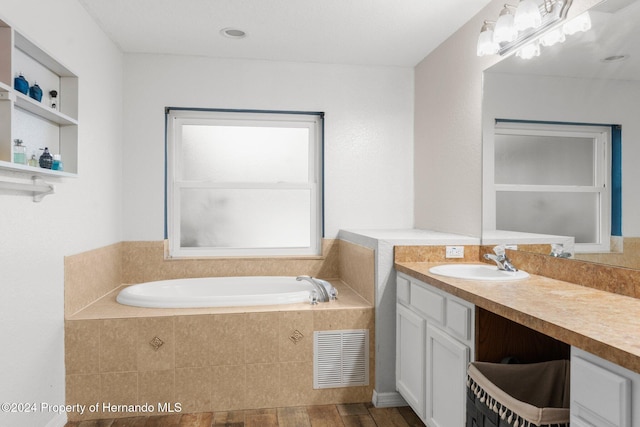 bathroom featuring vanity, hardwood / wood-style flooring, and a relaxing tiled tub