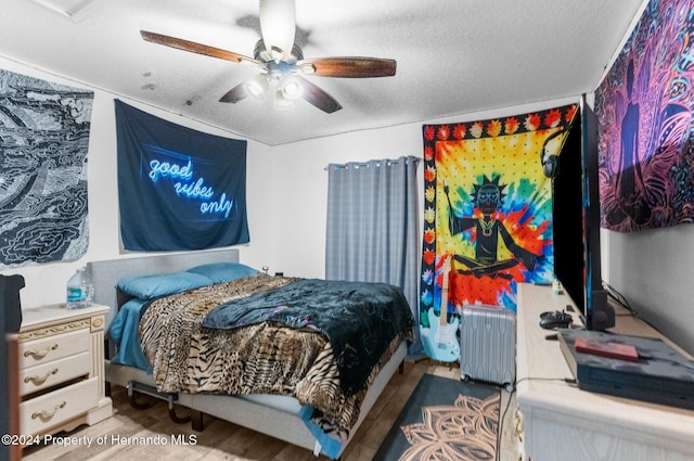 bedroom featuring a textured ceiling, hardwood / wood-style floors, ceiling fan, and radiator