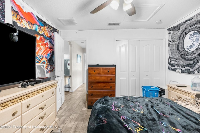 bedroom featuring ceiling fan, a textured ceiling, a closet, and light hardwood / wood-style flooring