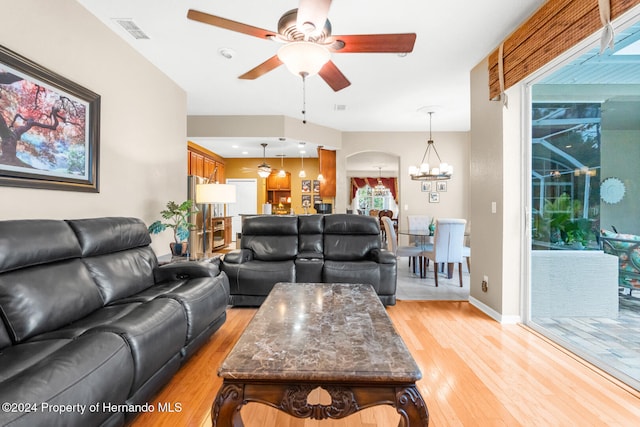 living room featuring ceiling fan with notable chandelier and light hardwood / wood-style flooring