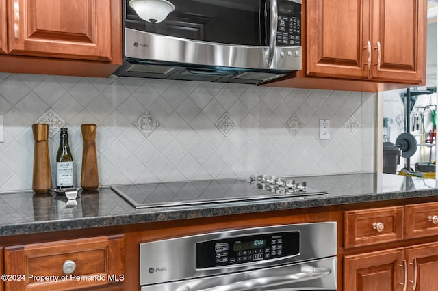 kitchen with backsplash, stainless steel appliances, and dark stone counters