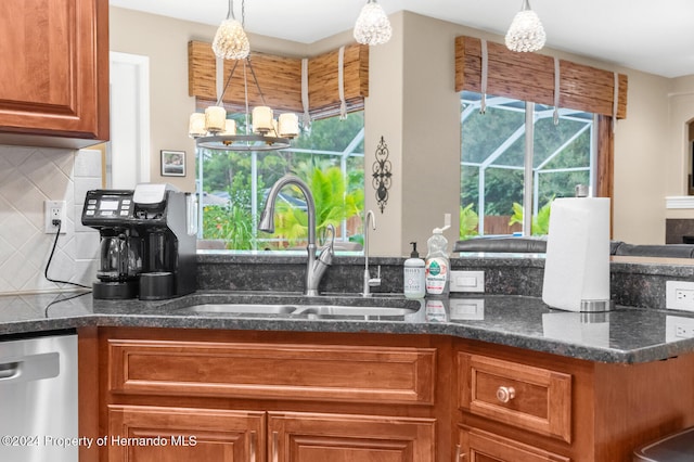 kitchen featuring pendant lighting, dishwasher, sink, tasteful backsplash, and a notable chandelier