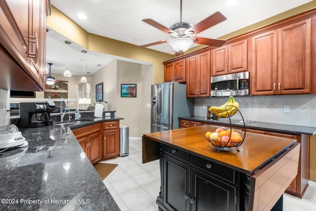 kitchen with sink, decorative backsplash, ceiling fan, dark stone countertops, and stainless steel appliances