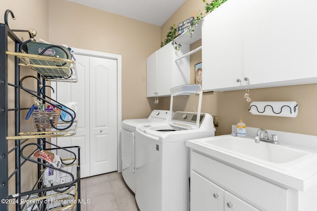 clothes washing area with washing machine and dryer, sink, light tile patterned floors, and cabinets