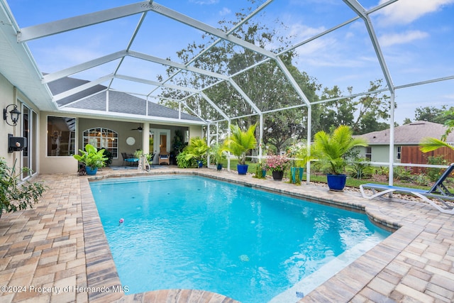 view of swimming pool with a lanai, ceiling fan, and a patio