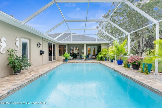 view of pool featuring glass enclosure and a patio