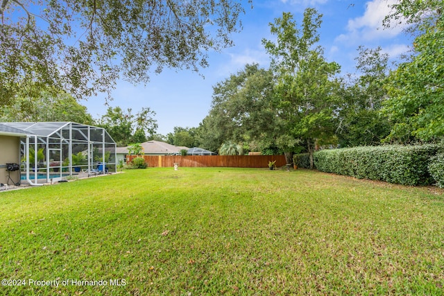 view of yard featuring glass enclosure and a swimming pool