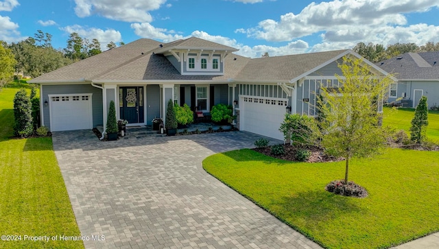 view of front of property featuring a front lawn, a garage, and covered porch