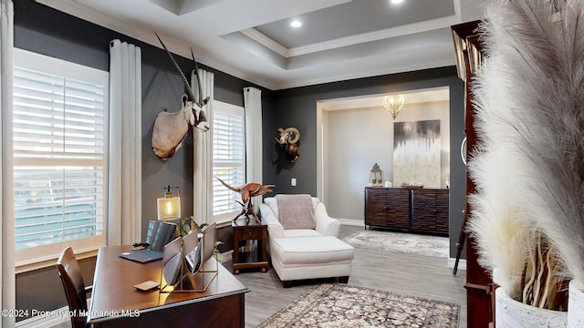 home office with light hardwood / wood-style floors, a raised ceiling, a healthy amount of sunlight, and crown molding